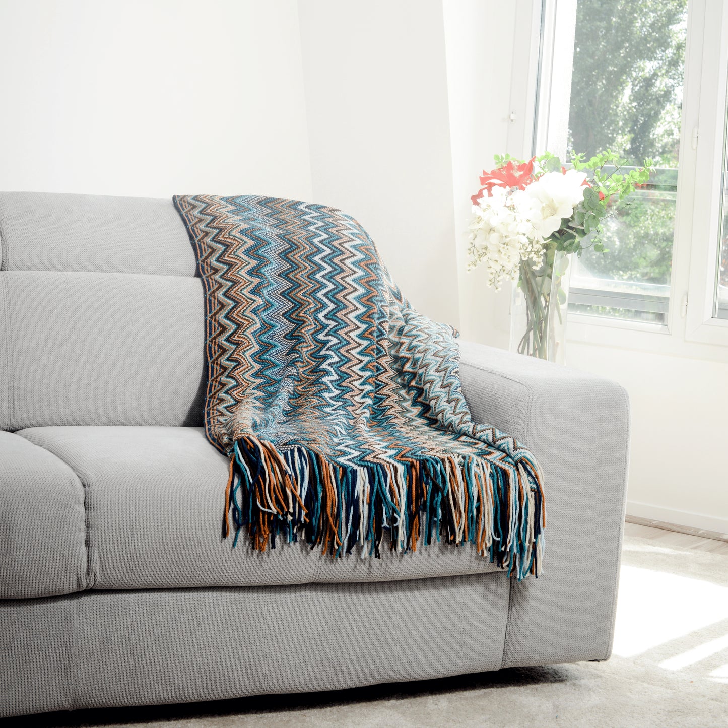 Plaid Bohème à motif posé sur un canapé dans un salon à l’ambiance cozy