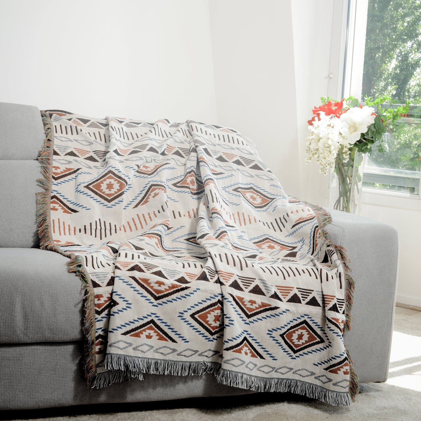Plaid Bohème à motif posé sur un canapé dans un salon à l’ambiance cozy