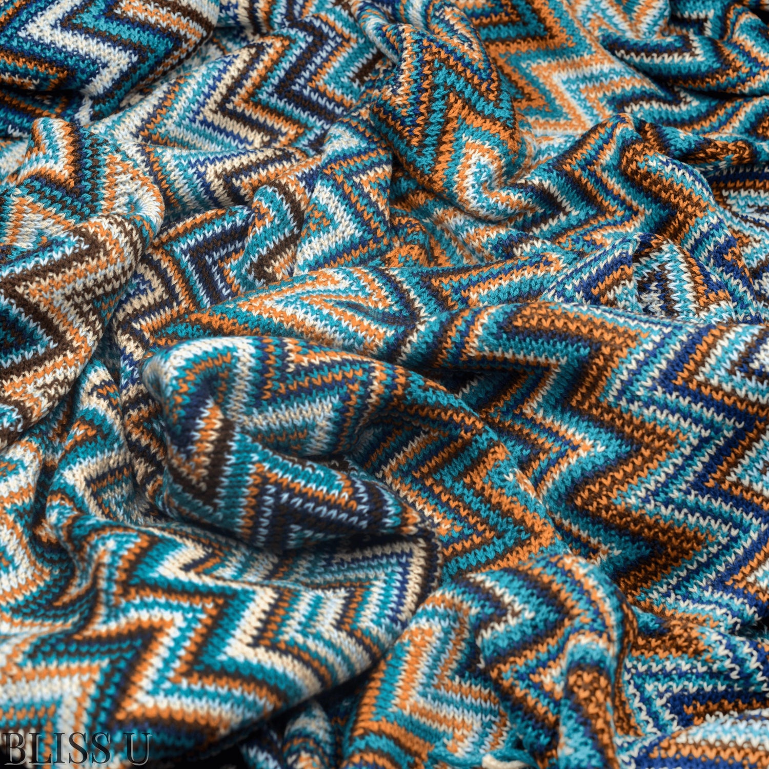 Couverture Plaid aux motifs Bohèmes froissés et vu de près avec le logo Bliss U