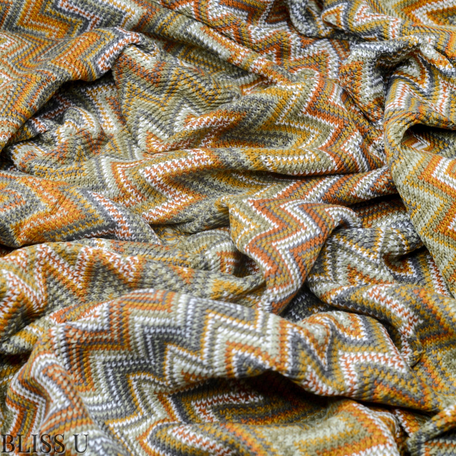 Couverture Plaid aux motifs Bohèmes froissés et vu de près avec le logo Bliss U