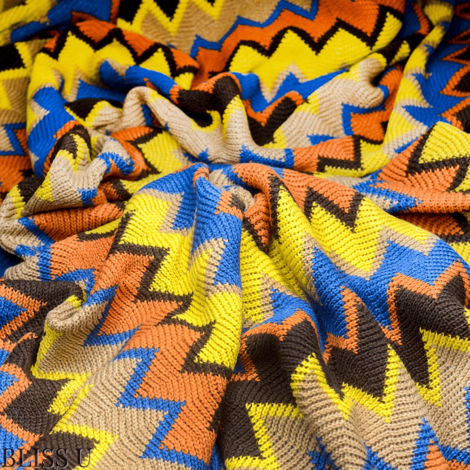 Couverture Plaid aux motifs Bohèmes froissés et vu de près avec le logo Bliss U