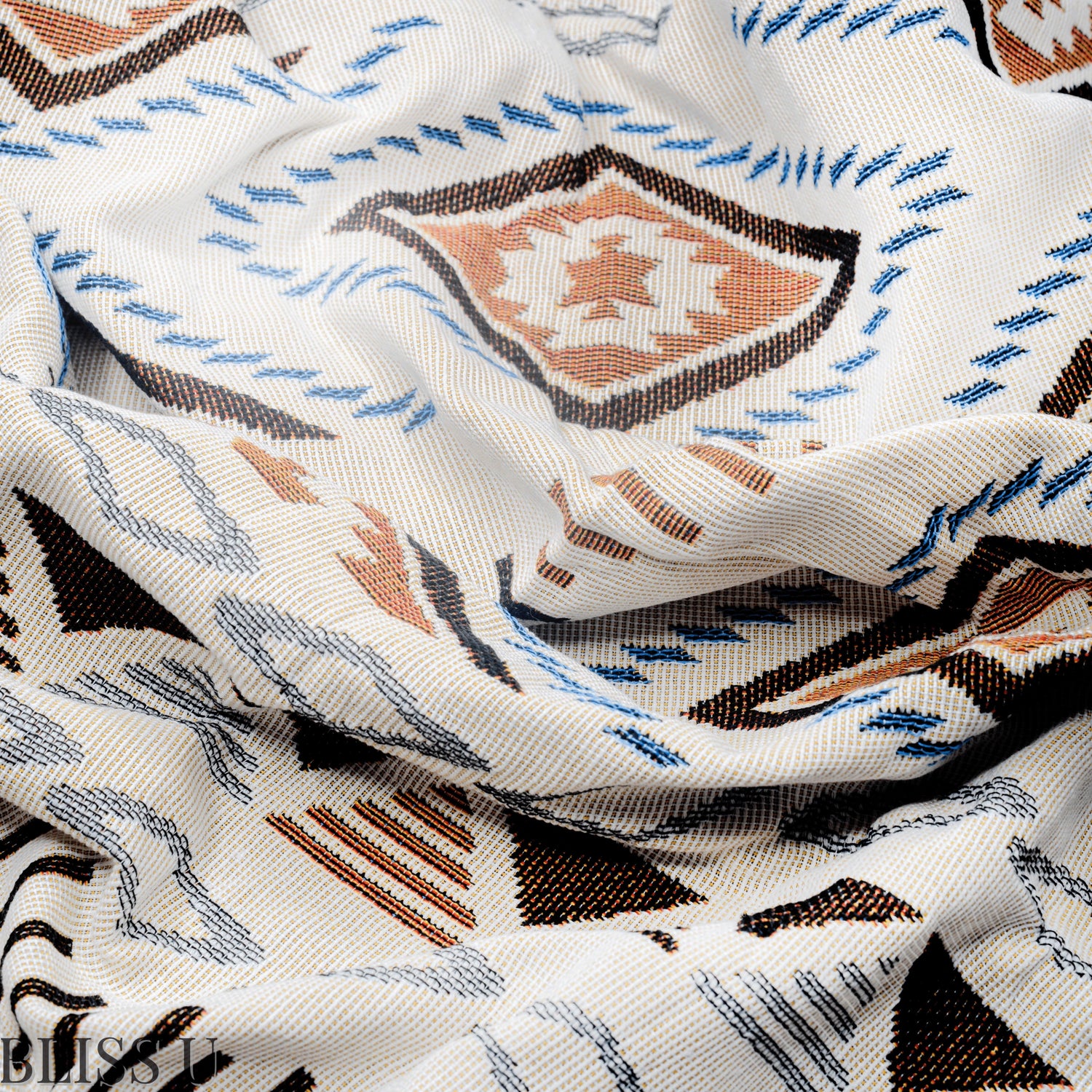 Couverture Plaid aux motifs Bohèmes froissés et vu de près avec le logo Bliss U