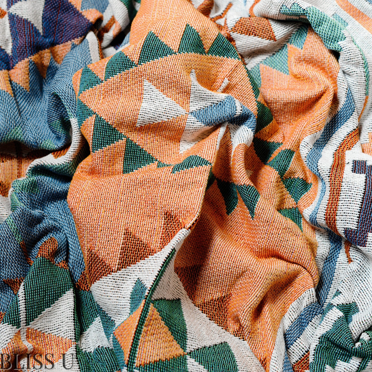 Couverture Plaid aux motifs Bohèmes froissés et vu de près avec le logo Bliss U