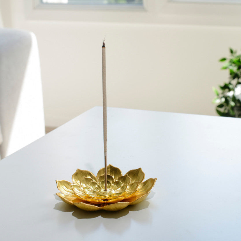 Porte encens bohème en forme de lotus doré posé sur une table dans un salon à l’ambiance cocooning