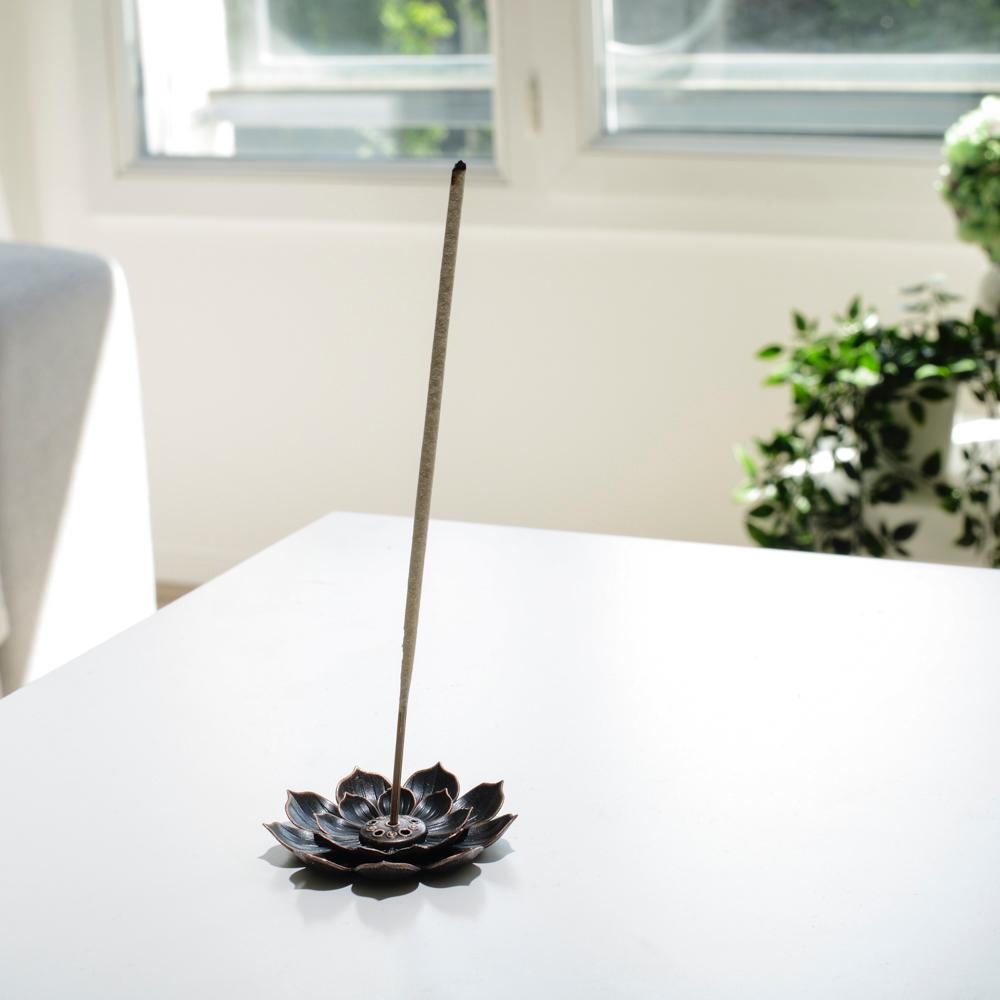 Porte encens bohème en forme de lotus posé sur une table dans un salon à l’ambiance cocooning