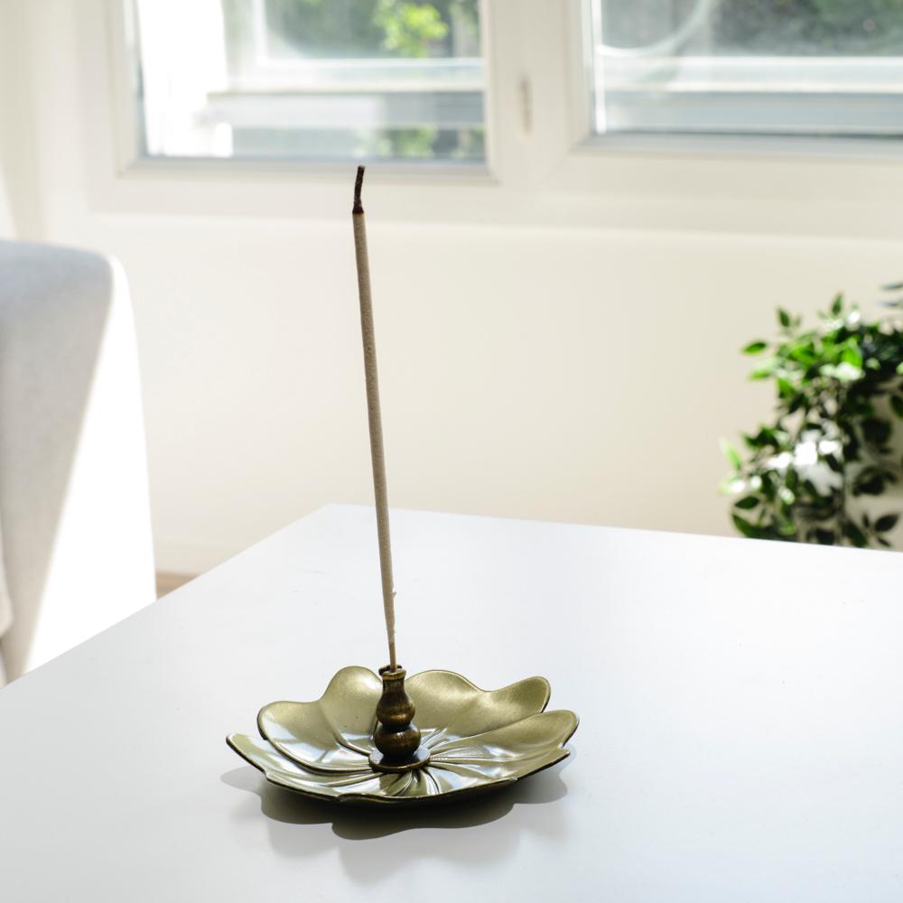Porte encens bohème en forme de lotus posé sur une table dans un salon à l’ambiance cocooning