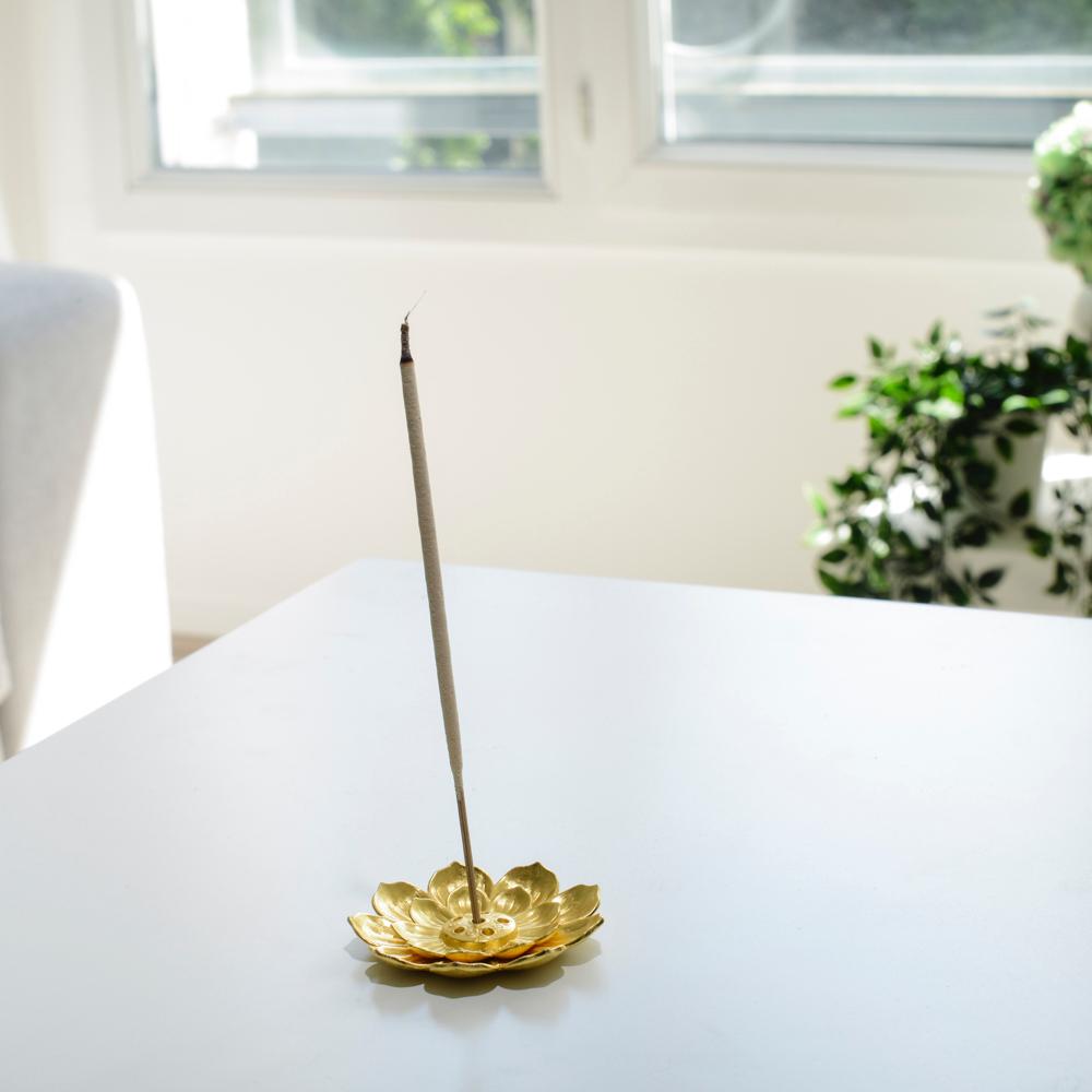 Porte encens bohème en forme de lotus doré posé sur une table dans un salon à l’ambiance cocooning