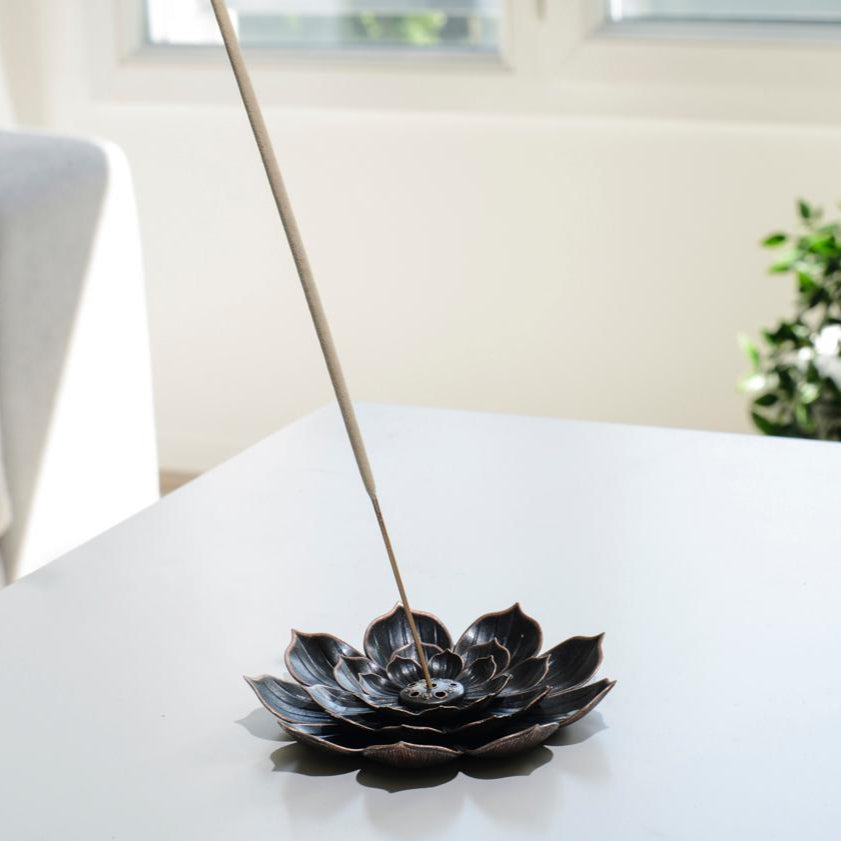 Porte encens bohème en forme de lotus posé sur une table dans un salon à l’ambiance cocooning