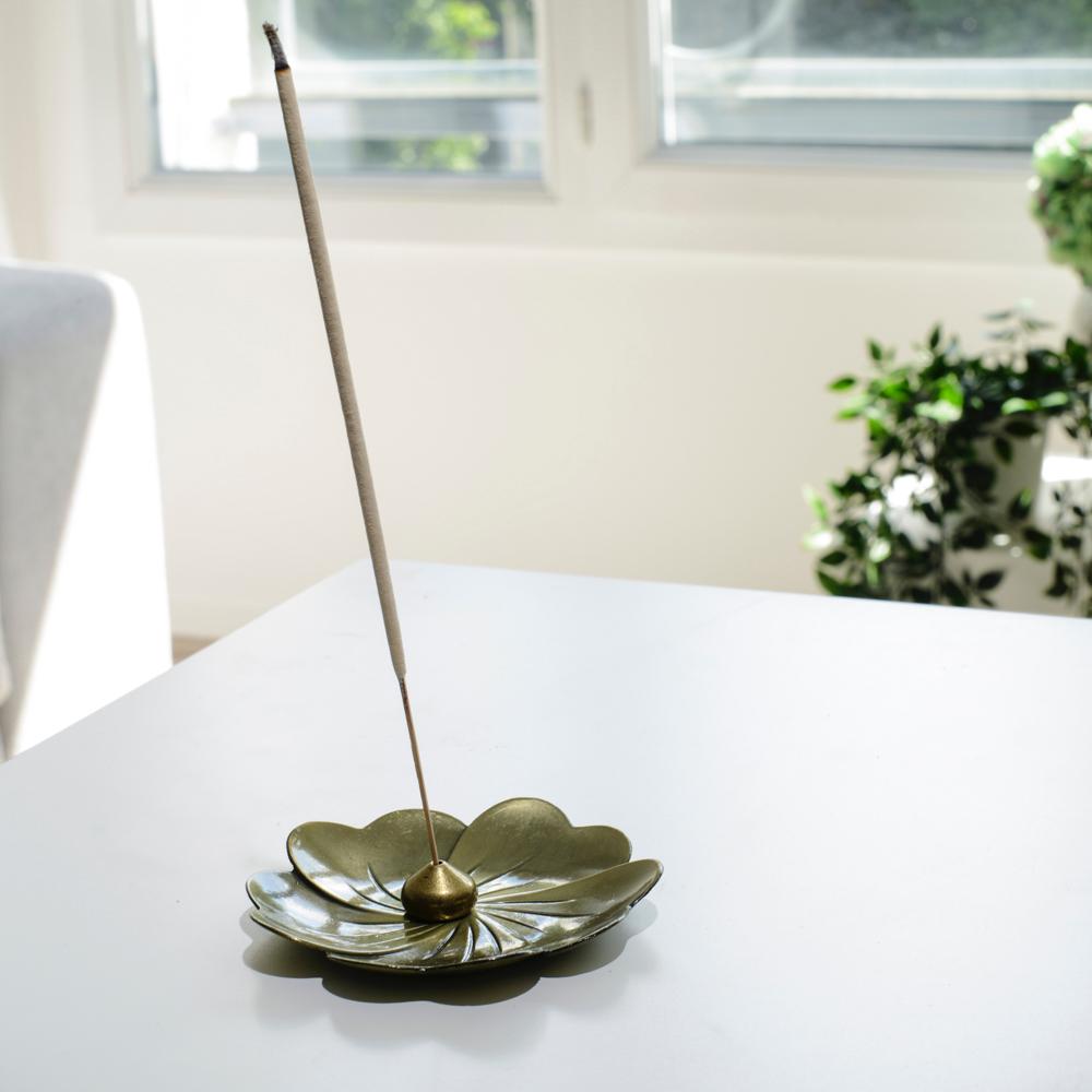 Porte encens bohème en forme de lotus posé sur une table dans un salon à l’ambiance cocooning