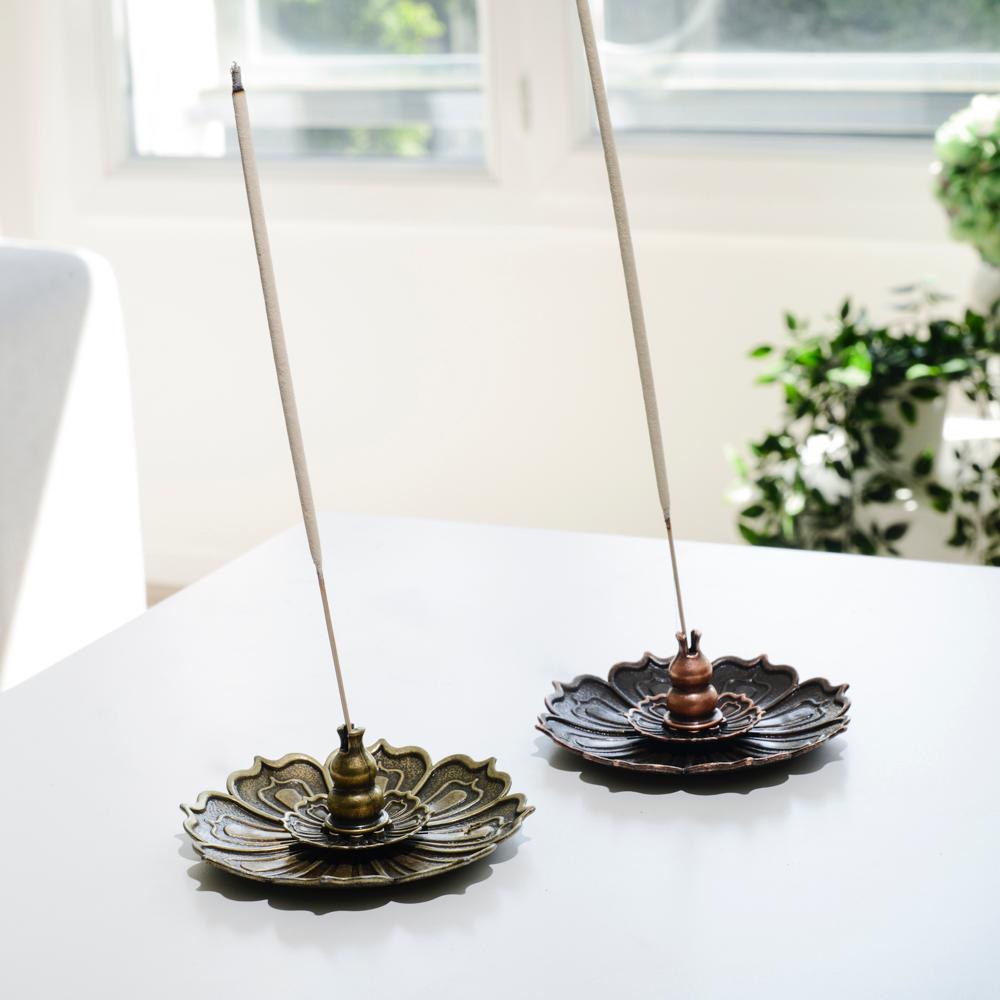 Porte encens bohème en forme de lotus de bronze posé sur une table dans un salon à l’ambiance cocooning