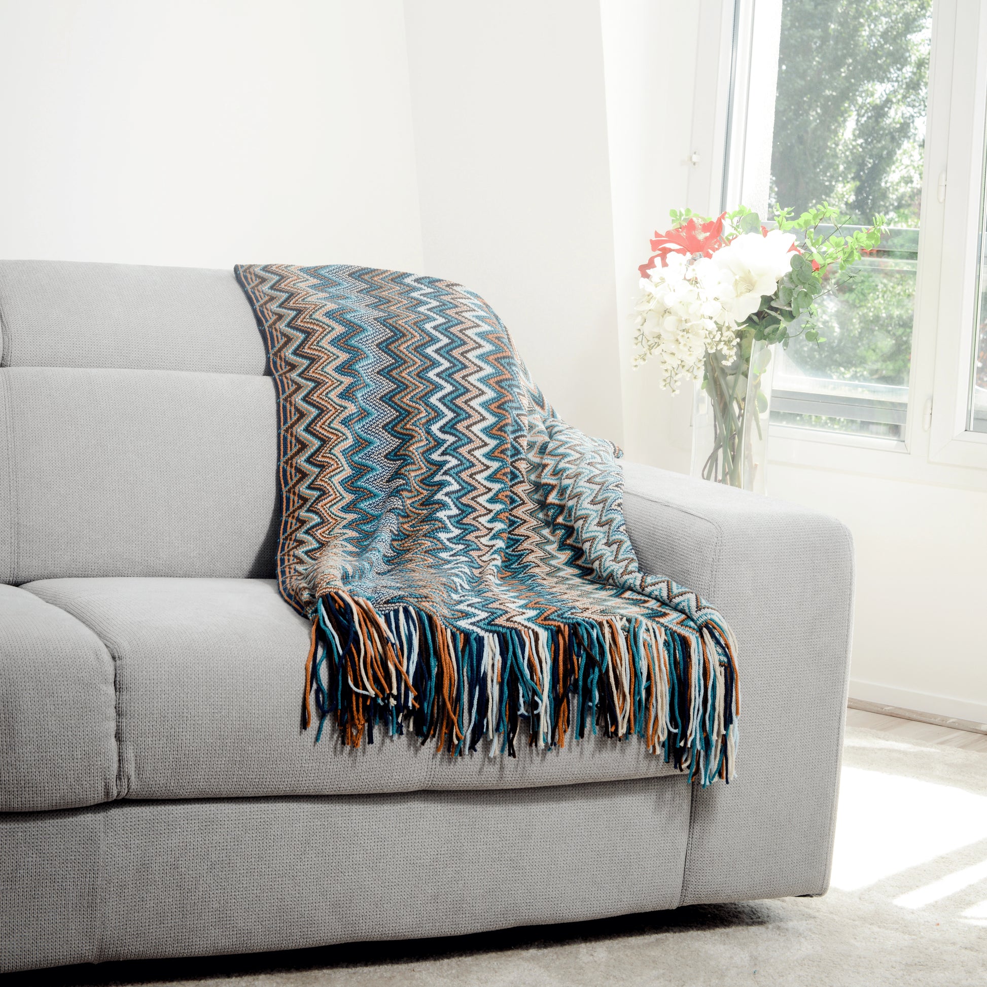 Plaid Bohème à motif posé sur un canapé dans un salon à l’ambiance cozy