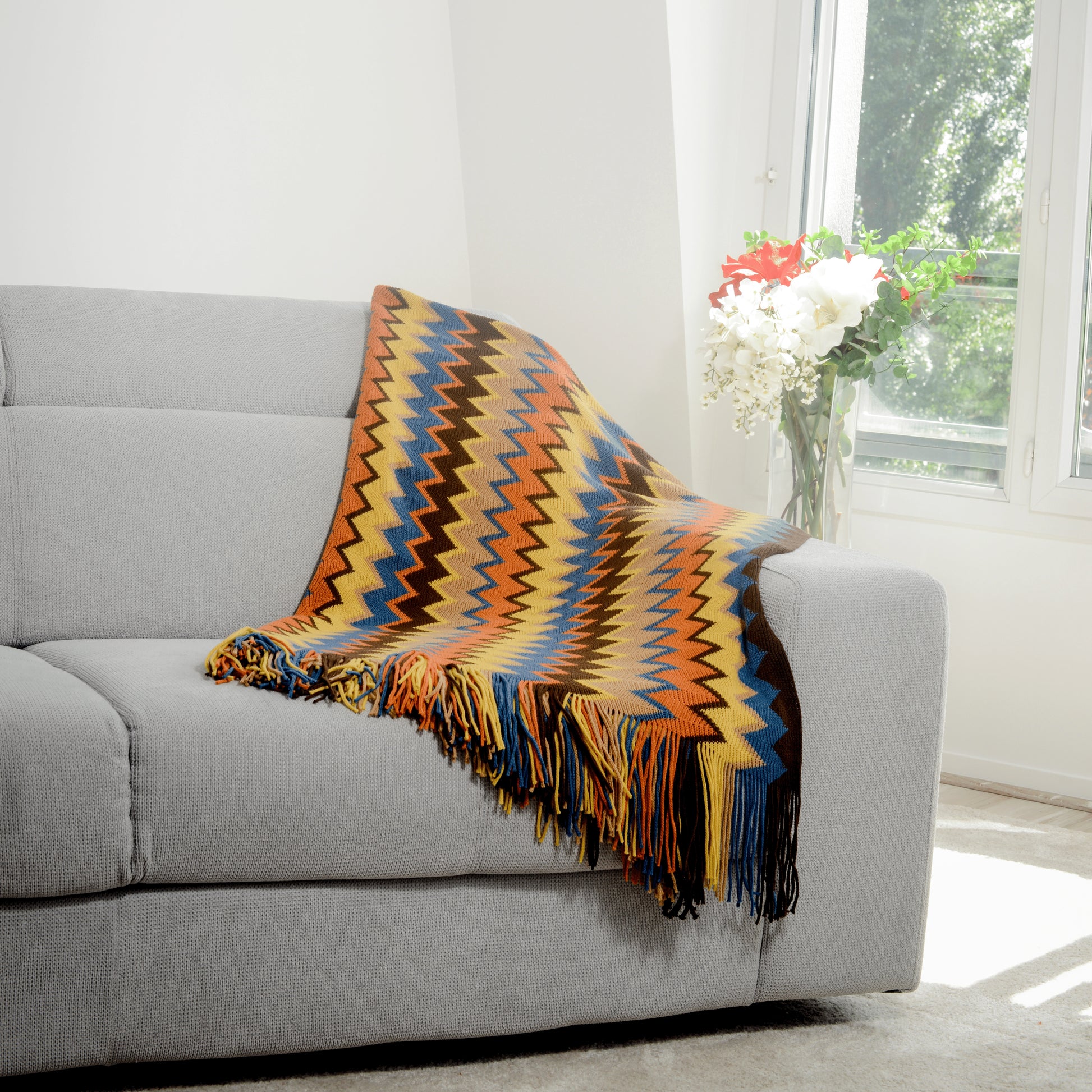 Plaid Bohème à motif posé sur un canapé dans un salon à l’ambiance cozy