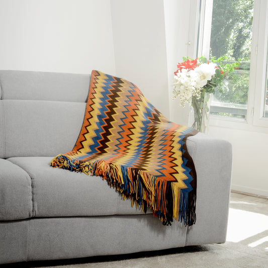 Plaid Bohème à motif posé sur un canapé dans un salon à l’ambiance cozy