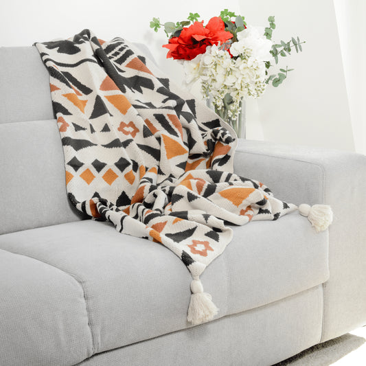 Plaid Bohème à motif posé sur un canapé dans un salon à l’ambiance cozy