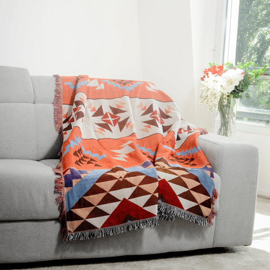 Plaid Bohème à motif posé sur un canapé dans un salon à l’ambiance cozy