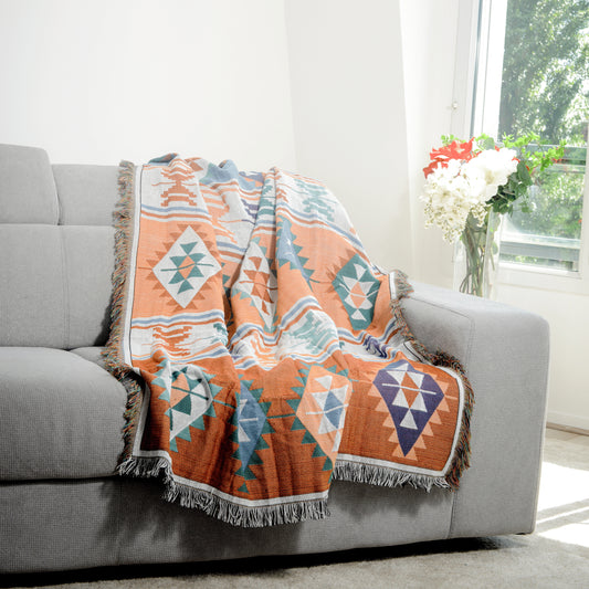 Plaid Bohème à motif posé sur un canapé dans un salon à l’ambiance cozy