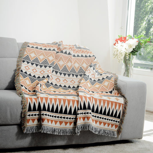 Plaid Bohème à motif posé sur un canapé dans un salon à l’ambiance cozy