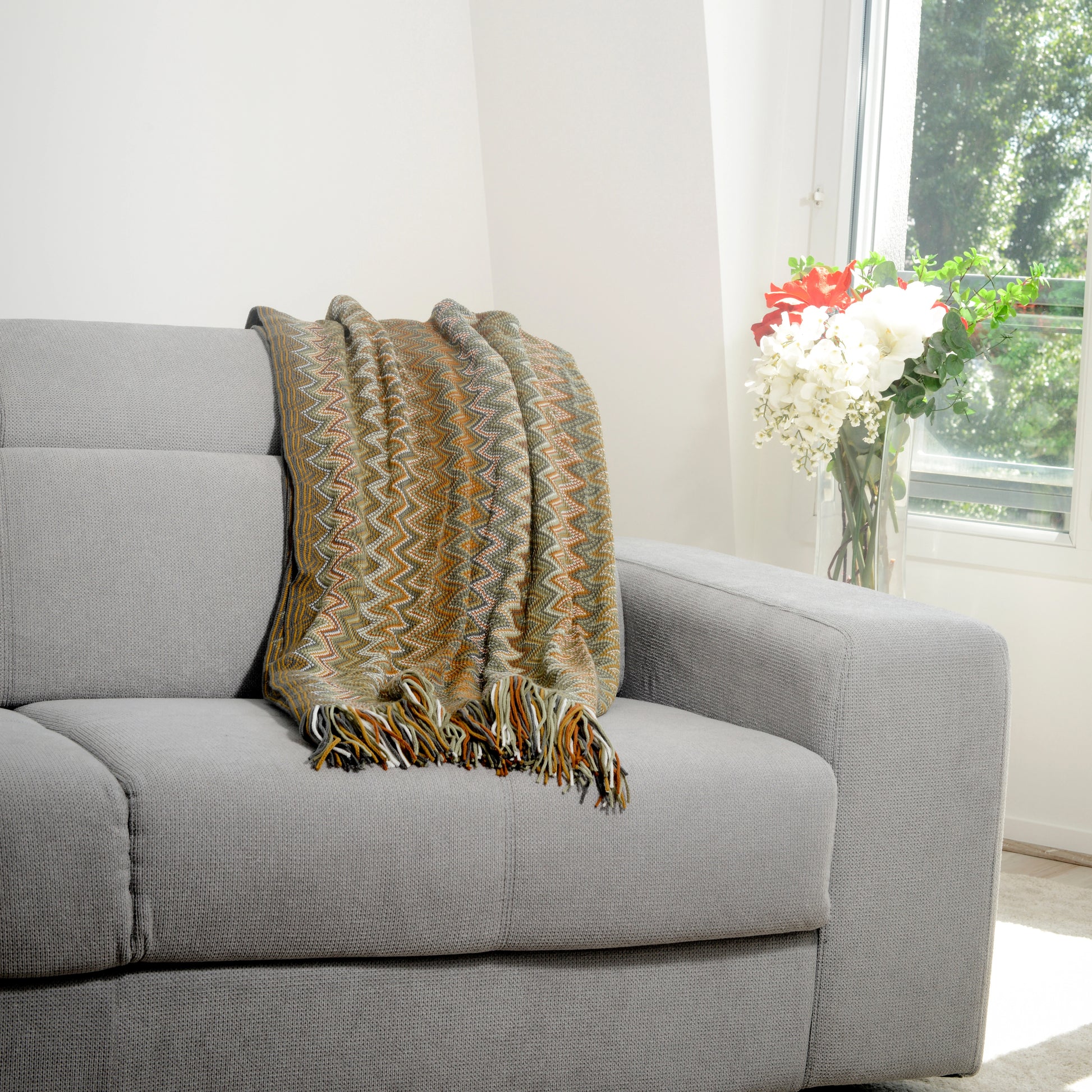 Plaid Bohème à motif posé sur un canapé dans un salon à l’ambiance cozy