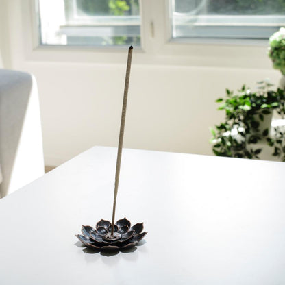 Porte encens bohème en forme de lotus posé sur une table dans un salon à l’ambiance cocooning