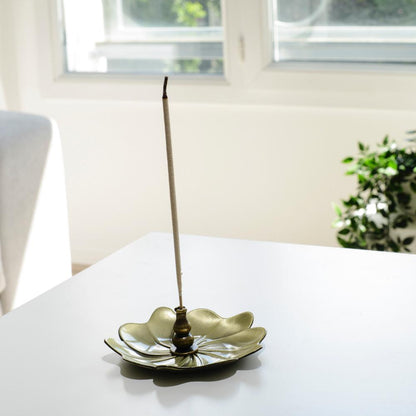 Porte encens bohème en forme de lotus posé sur une table dans un salon à l’ambiance cocooning