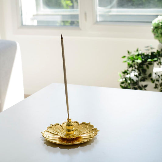 Porte encens bohème en forme de lotus doré posé sur une table dans un salon à l’ambiance cocooning