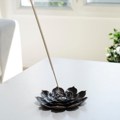 Porte encens bohème en forme de lotus posé sur une table dans un salon à l’ambiance cocooning